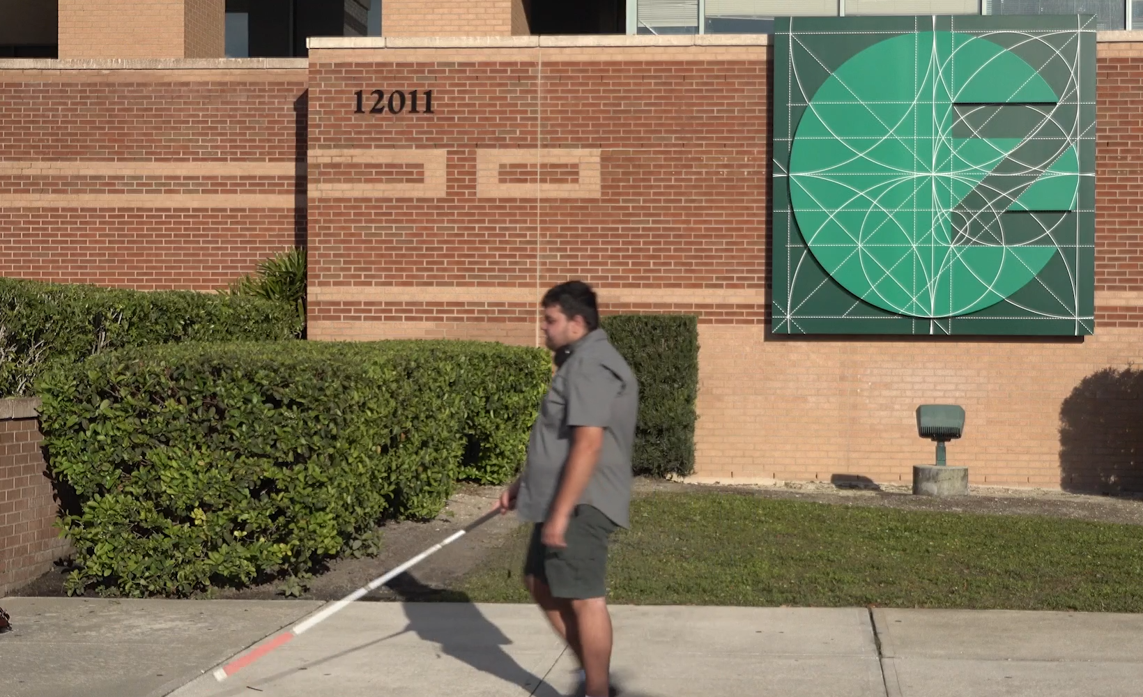 Trent uses his cane to walk in front of the Zimmerman School