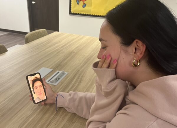 A college student sits at a table and talks on her mobile phone with her long-distance boyfriend