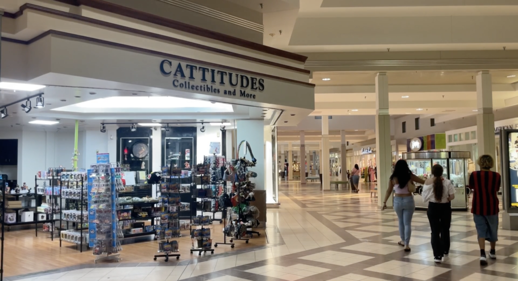 Three people walking next to stores at the mall