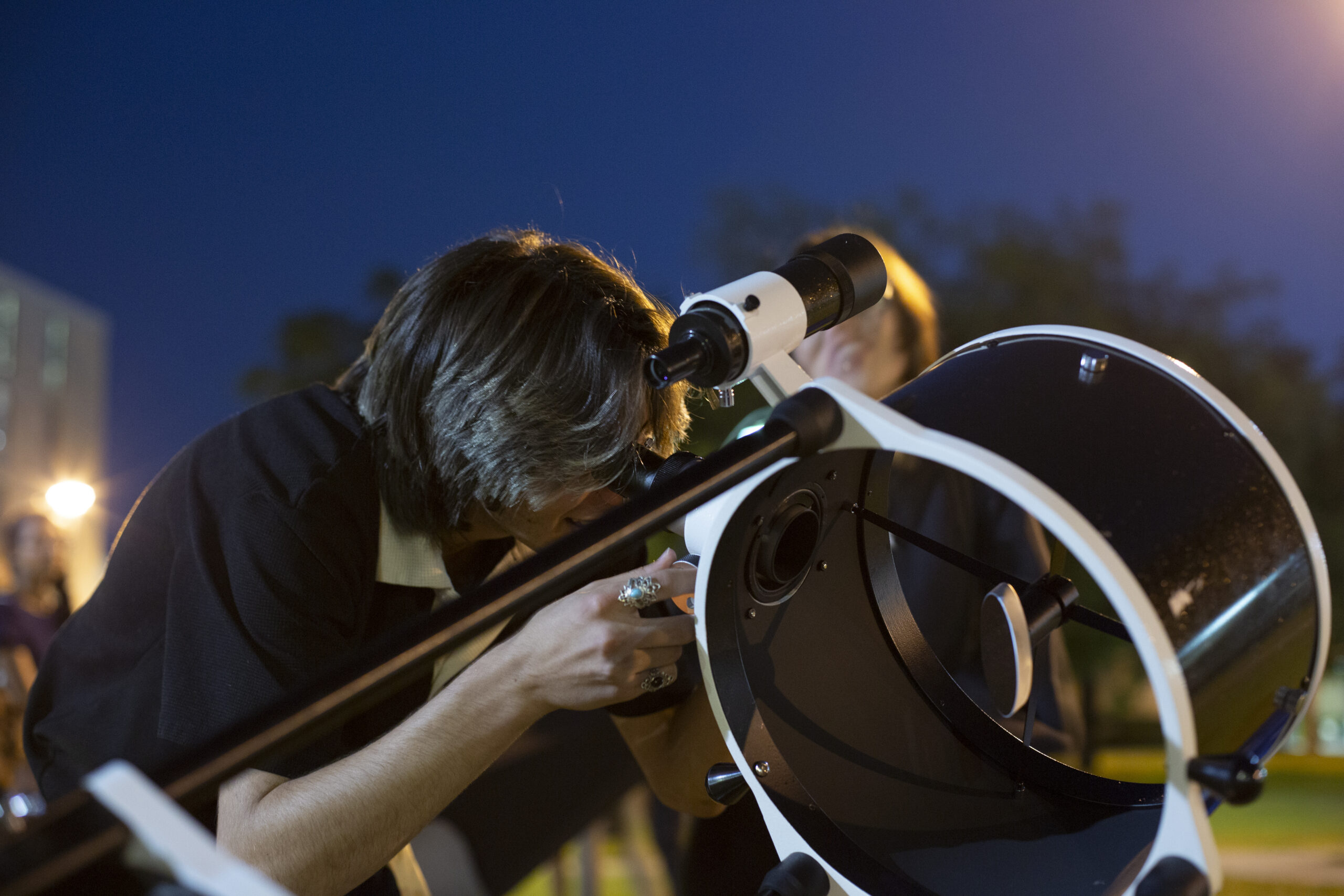 A student looking into a telescope at the Stargazing at Magnolia Fields event