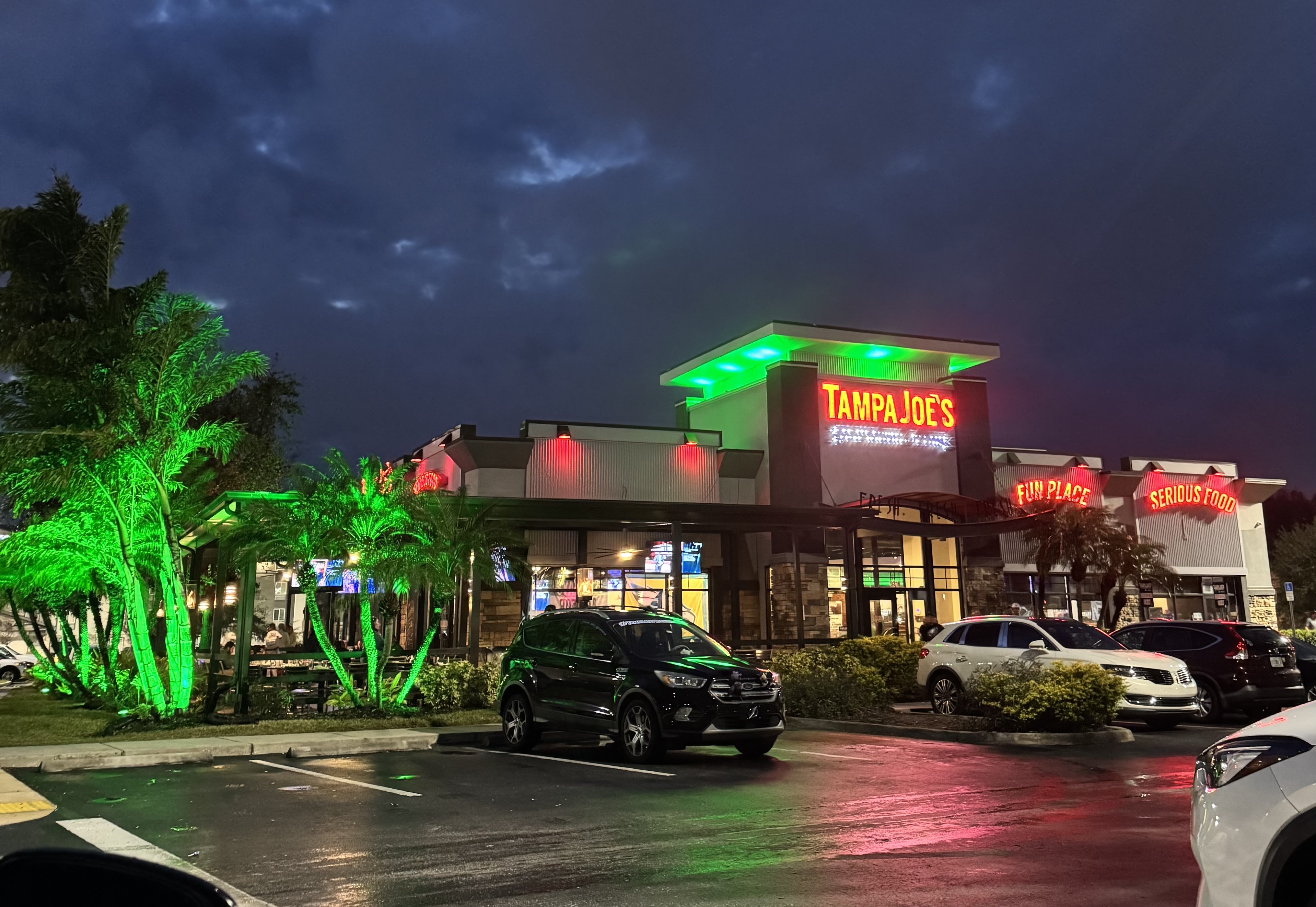 The outside of restaurant Tampa Joe's lit up with green lights.