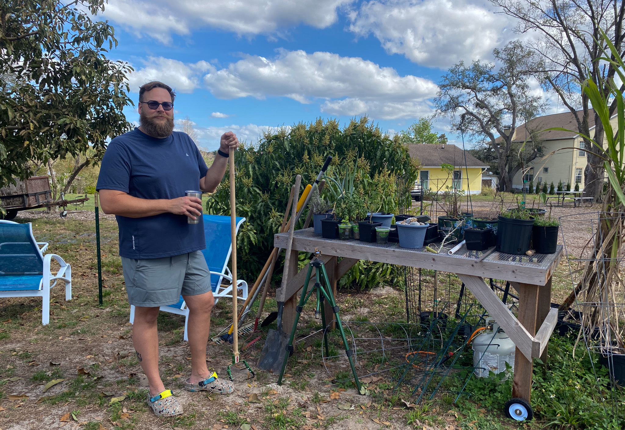 Tyler Singleton stands next to his "clutter". Behind the garden area is the house he bought in 2020.