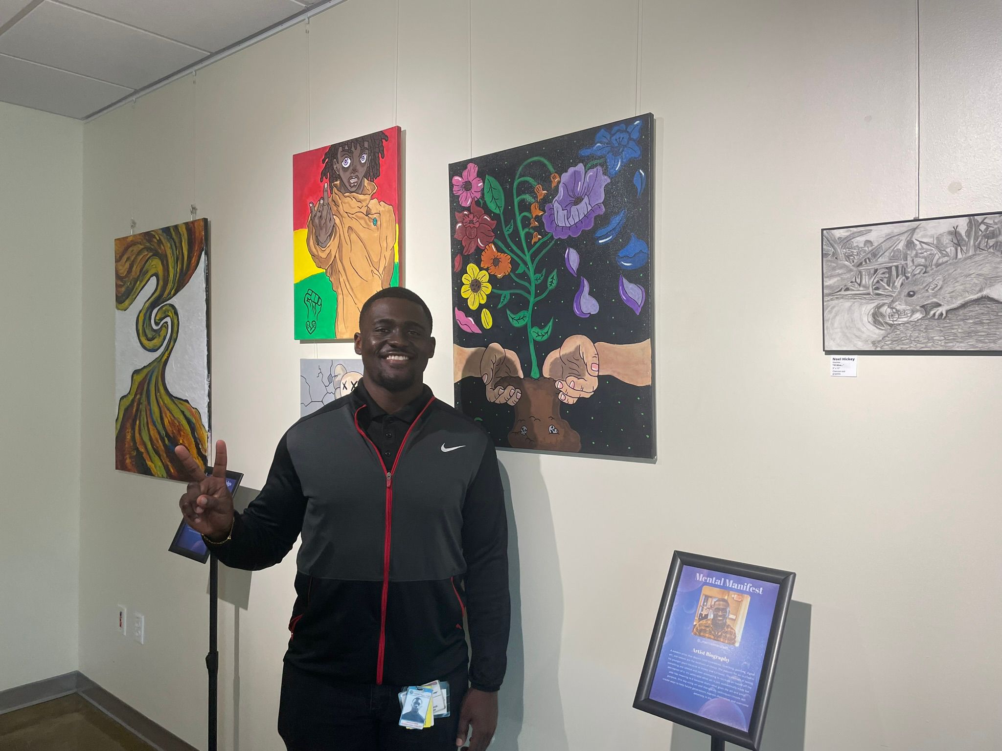 Lincoln Esmie Jr. stands in front of the three paintings he contributed to "Odds and Ends."