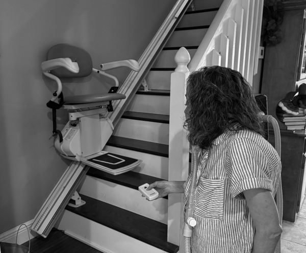 Woman pressing button on remote to bring down her stair climber.
