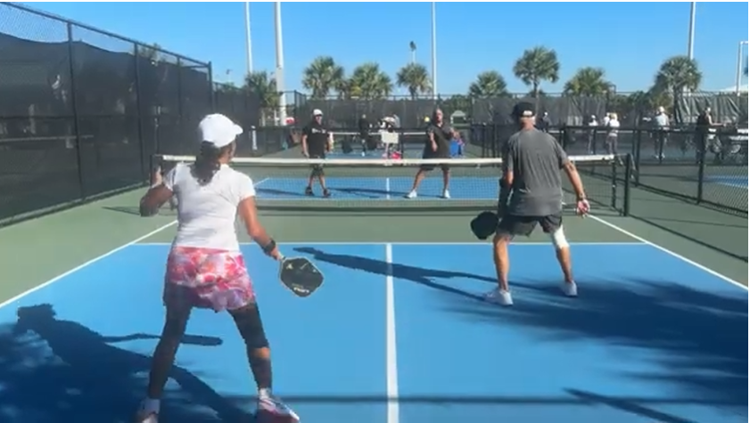 Two couples playing pickleball on a blue court in Naples, Florida
