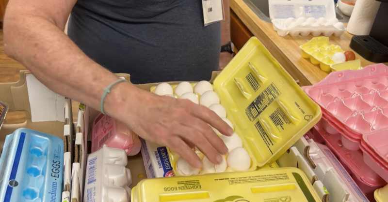A food pantry volunteer handles eggs in the carton