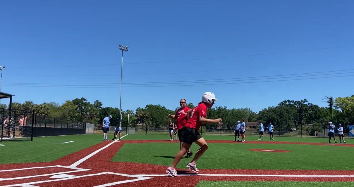A baseball diamond with a batter running to first base in the foreground