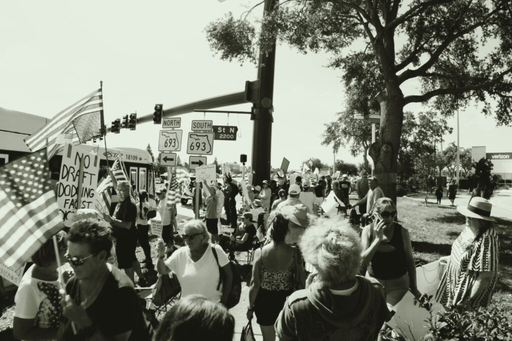 A black and white photo of a crowd of protestors holding signs and American flags.