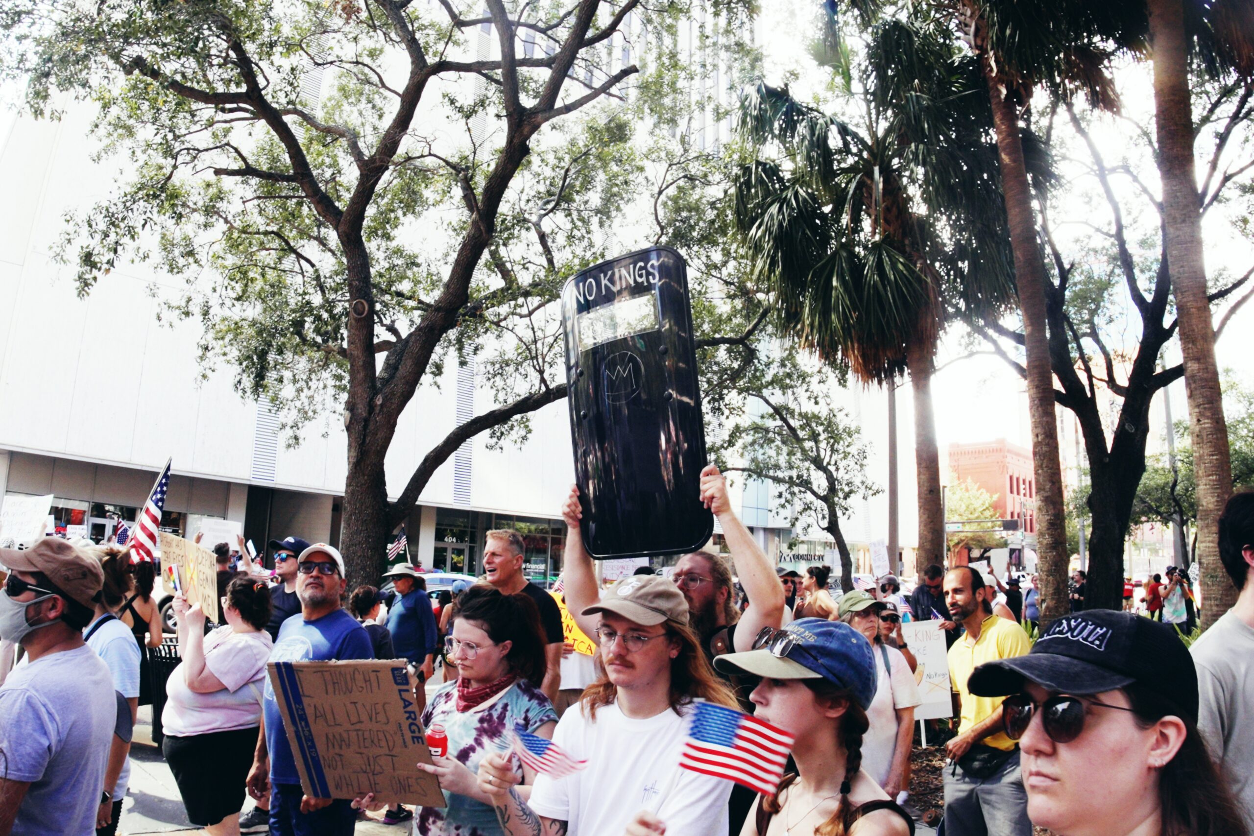 A man holding a riot shield with the words "No Kings" amongst a crowd of protestors.