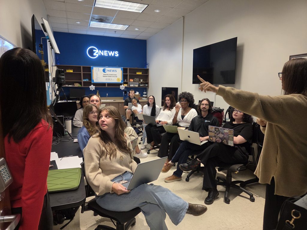 This is the Z News newsroom with multiple students sitting looking at a teacher teach